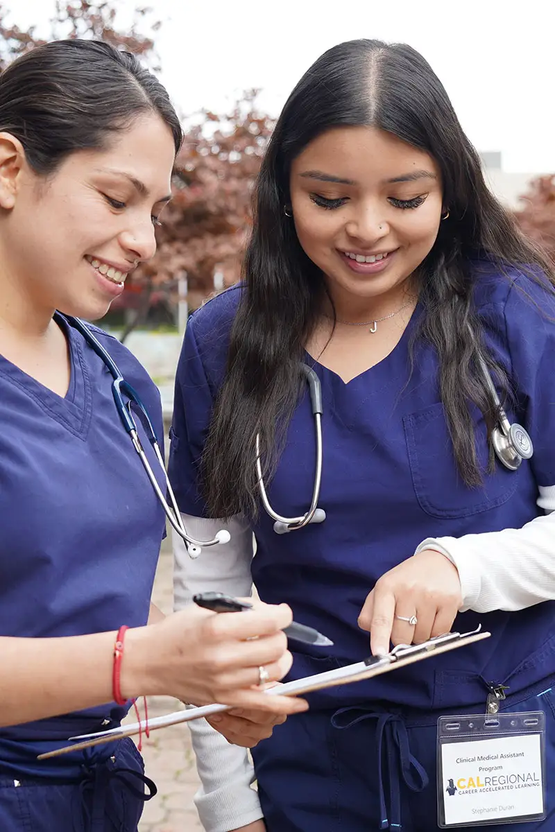 Two female medical students checking clipboard